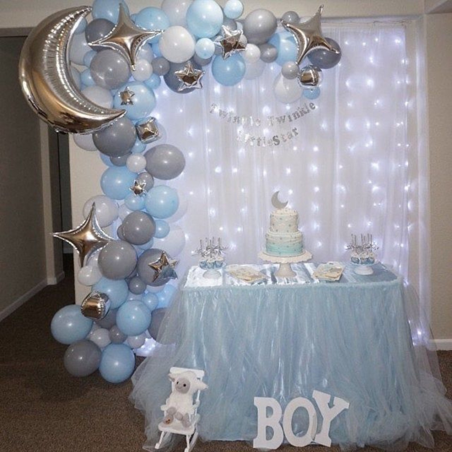 Decoración de baby shower azul para niño con arco de globos y luces